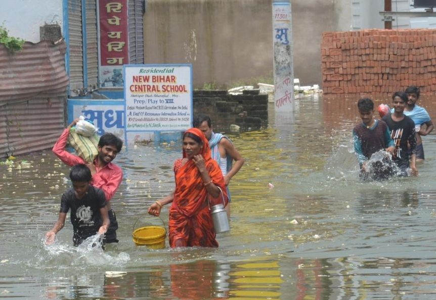 Muzaffarpur: People brave the flood waters as they move to safer places in Bihar’s flood-hit Muzaffarpur district on July 26, 2020. (Photo: IANS)